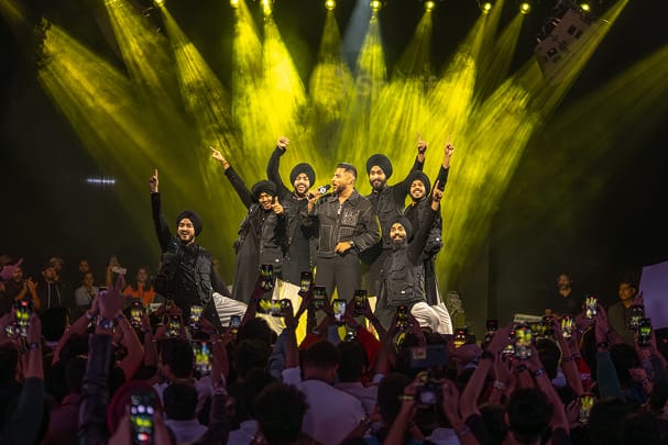 Karan Aujla performing on a stage with audience capturing the moment on their phones