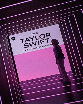 Siluet seseorang yang berdiri di depan latar bercahaya dengan tulisan 'This is Taylor Swift' di atasnya