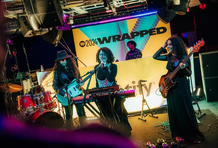 Seera singing and playing the piano with the band around her