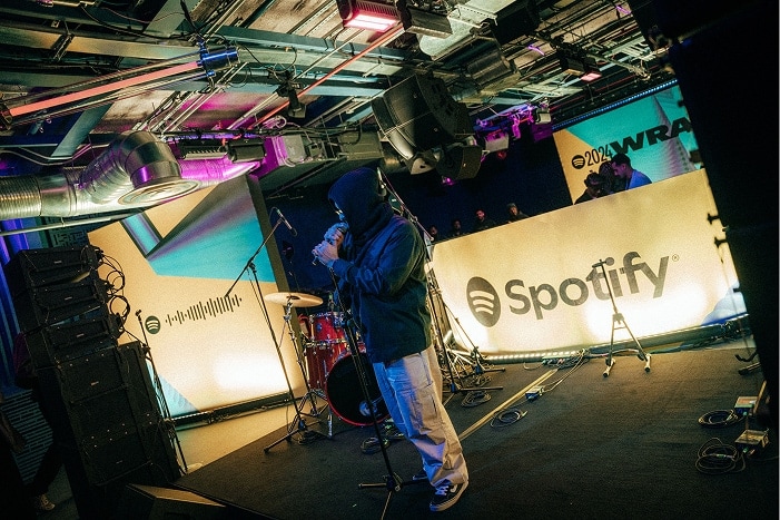 Grizzzzlee on the stage with a mic in hand with Spotify 2024 Wrapped branding in the background