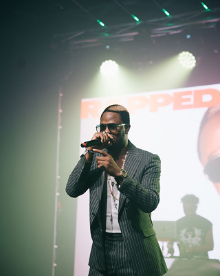 Fido with a mic in hand and one of his band members in the background, lit by Spotify Wrapped branding