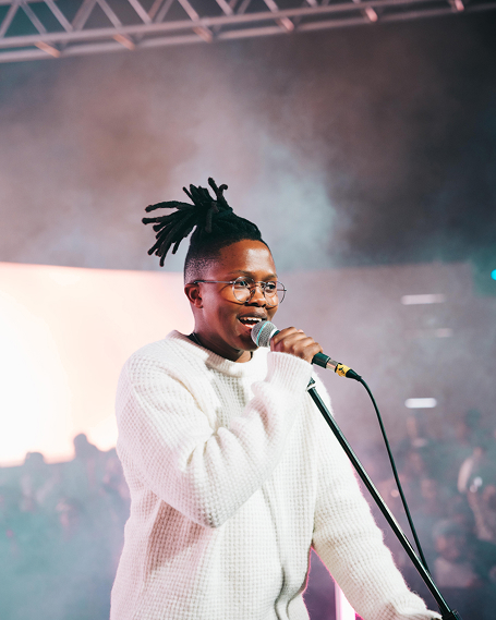 Manana singing into the mic on a brightly lit stage