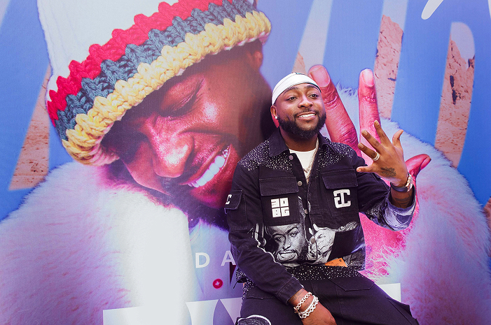 Davido posing in front of a picture of him at an event